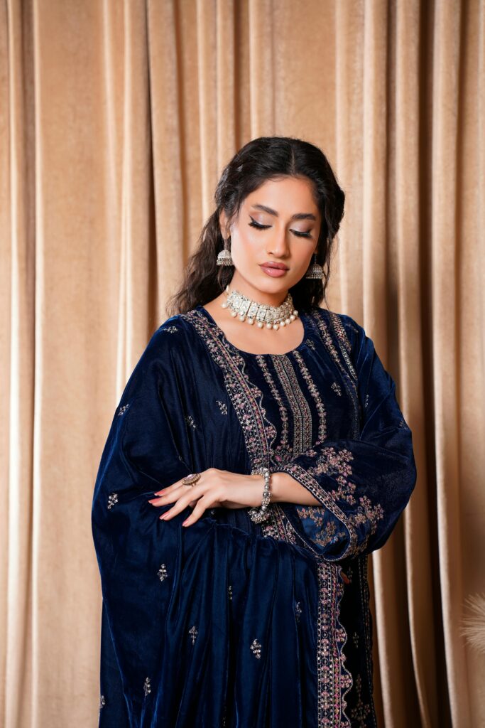 Close-up portrait of a woman in an embroidered velvet dress, showcasing traditional Pakistani fashion.